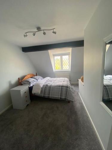 a bedroom with a bed and a window and a mirror at Family Home In The Forest Of Dean in Coleford