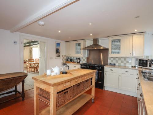 a kitchen with white cabinets and a wooden counter top at Plas in Rhoscolyn