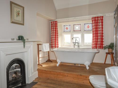 a bath tub in a room with a fireplace at Plas in Rhoscolyn