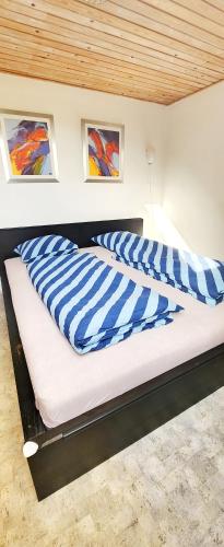 a bed with blue and white striped pillows on it at Quiet and cozy apartment close to nature in villa. in Tilst