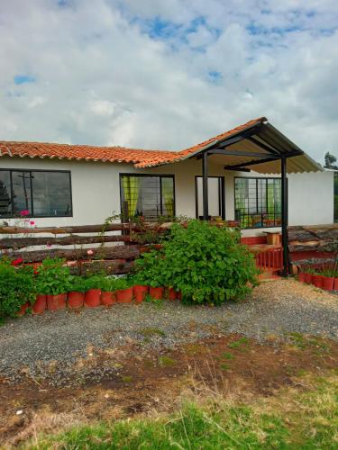 a white house with a roof and some plants at Casa Campo La Milagrosa in Cómbita