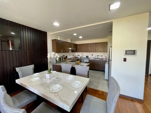 a kitchen and dining room with a table and chairs at Maravilloso departamento con moto electricá in Cuenca