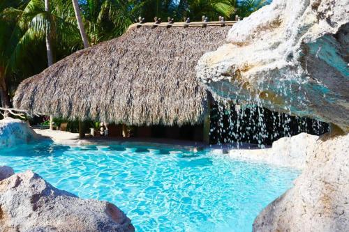 a resort swimming pool with a thatch roof at Bungalows Sugarloaf Beach Key West - Hammock House in Sugarloaf Shores
