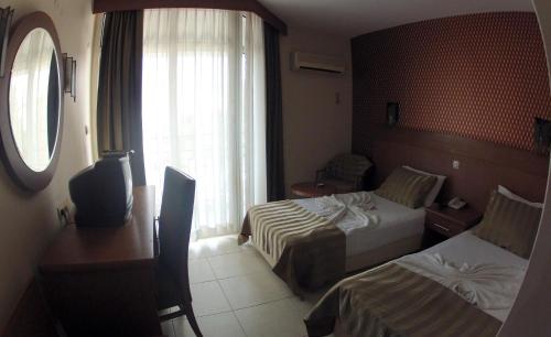 a hotel room with two beds and a desk and a window at Surtel Hotel in Kusadası