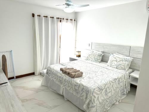 a white bedroom with a large bed with a window at Villa Ferradura Mar in Búzios