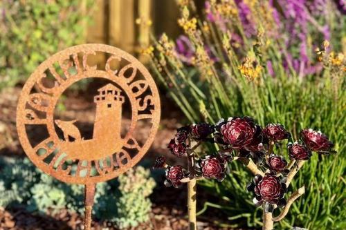 a sign in front of a garden with flowers at Sand Dollar Shore in Fort Bragg