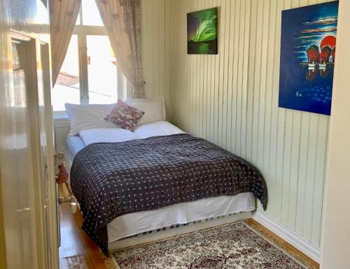 ein kleines Bett in einem Zimmer mit Fenster in der Unterkunft Angelas White House in Stamsund