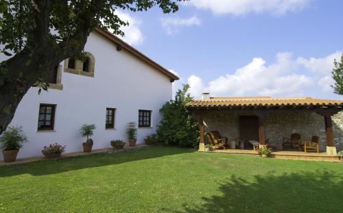 a white house with a patio and a yard at Posada La Casona de Los Güelitos in Santillana del Mar