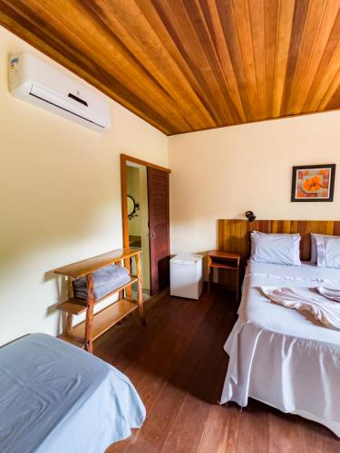 a bedroom with two beds and a wooden ceiling at Pousada da Fonte in Lençóis