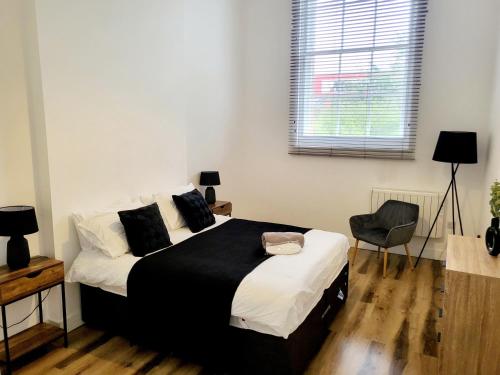 a bedroom with a black and white bed and a chair at Burkhardt Hall- Parking Included- Sleeps 4 in Swindon