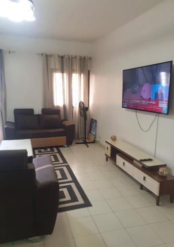 un salon avec un canapé et une télévision à écran plat dans l'établissement Le zèbre, à Dakar