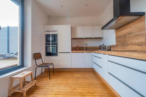 une cuisine avec des placards blancs, une chaise et une fenêtre dans l'établissement Champagne Sunset, à Gueux