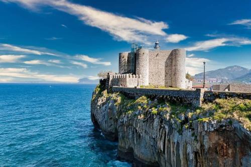 a building on a cliff next to the ocean at Jumeke Home in Castro-Urdiales