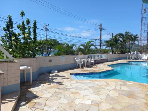 a swimming pool with a patio and a fence at Apartamento de Frente para o Mar in Ubatuba