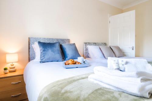 a bedroom with two beds with blue and white pillows at Beautiful Gloster House with a Large Garden & Free Parking in Woking