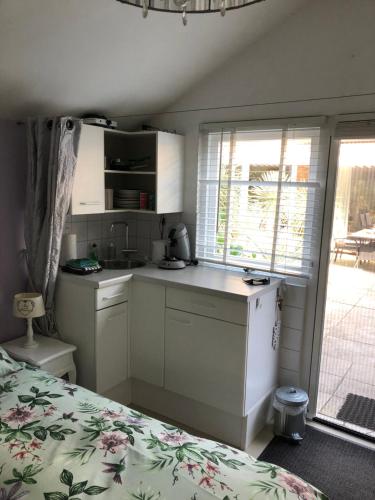 a small kitchen with a bed and a window at Romantisch Tiny Gardenhouse in beautiful garden in Zandvoort