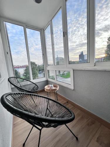 a room with windows and a chair and a table at Greywood relax apartment in Zagreb