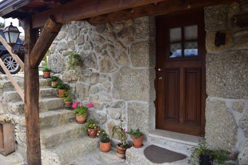 a stone house with a wooden door and potted plants at Casinha Estrela da Encosta - Gerês in Vieira do Minho