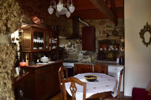 eine Küche mit einem Tisch, einem Herd und einer Arbeitsplatte in der Unterkunft Casinha Estrela da Encosta - Gerês in Vieira do Minho