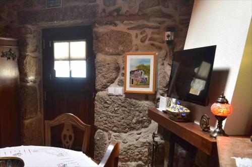 a room with a stone wall with a door and a television at Casinha Estrela da Encosta - Gerês in Vieira do Minho