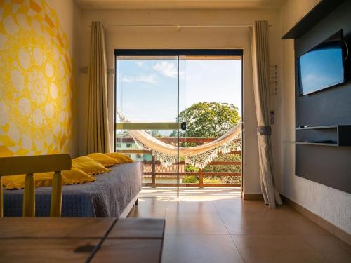 1 dormitorio con 1 cama y puerta corredera de cristal en Lugar ao Sol - Flats - Praia do Rosa - SC en Praia do Rosa