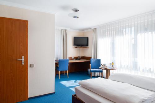 a hotel room with a bed and a desk and a television at Garni-Hotel Sailer & Hotel Sailer´s Villa in Rottweil