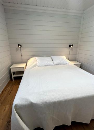 a bedroom with a large white bed with two lamps at Himos Alahonka B in Jämsä