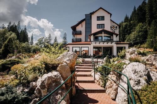 una casa en la cima de una colina con algunas rocas en Hotel Lacu Rosu, en Lacu Roșu