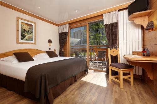 a bedroom with a bed and a desk and a window at Hôtel de L'Arve by HappyCulture in Chamonix