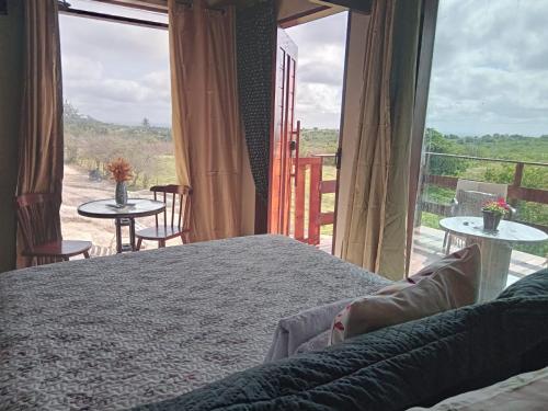 ein Schlafzimmer mit einem Bett und einem großen Fenster in der Unterkunft Chalé Adventure in Nova Cruz
