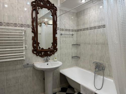 ein Badezimmer mit einem Waschbecken, einer Badewanne und einem Spiegel in der Unterkunft Апартаменты на Бориса Гринченка in Kiew
