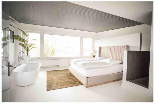 a white bedroom with a bed and a bath tub at Ivory (car) loft / Carloft in Neuwied