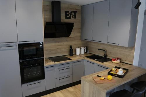 a kitchen with white cabinets and a wooden counter top at Avangard HOME II in Rokovci