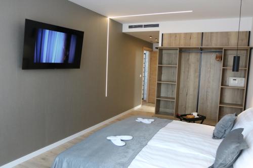 a bedroom with a bed with a tv on the wall at Avangard HOME II in Rokovci