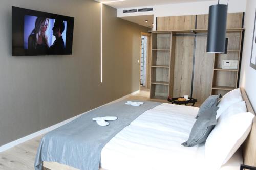 a bedroom with a bed with a tv on the wall at Avangard HOME II in Rokovci