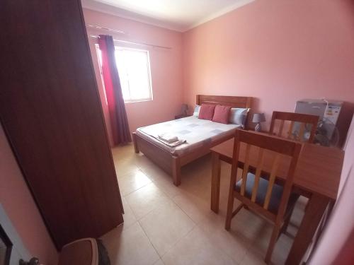 Schlafzimmer mit einem Bett, einem Tisch und einem Fenster in der Unterkunft Casa Barreto in Tarrafal