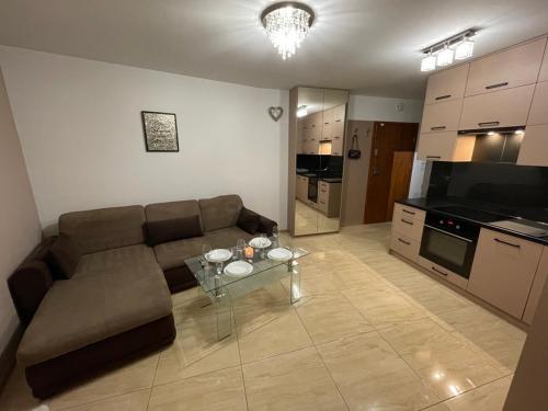 a living room with a couch and a glass table at Apartament Głowackiego 10 in Koszalin