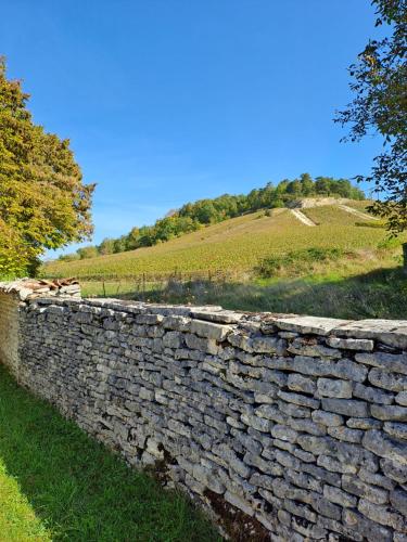 a stone wall with a hill in the background at Le val d Arlette in Arsonval