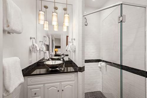 a white bathroom with a sink and a shower at Independence Square 302, Top Floor Stylish Hotel Room with Wet Bar, A/C, in Downtown Aspen in Aspen