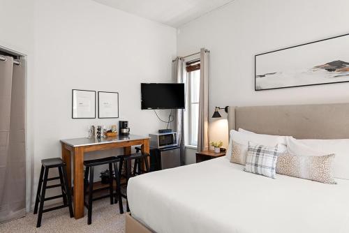 a bedroom with a bed and a desk with a television at Independence Square 211, Chic Hotel Room with Mountain Views, A/C, & Rooftop Hot Tub in Aspen