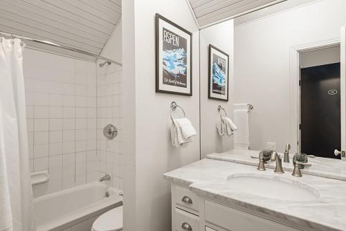 a white bathroom with a sink and a tub and a toilet at Independence Square 211, Chic Hotel Room with Mountain Views, A/C, & Rooftop Hot Tub in Aspen