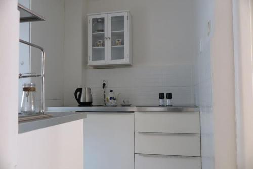 uma cozinha branca com armários brancos e um lavatório em Hradčany apartment with green energy em Praga