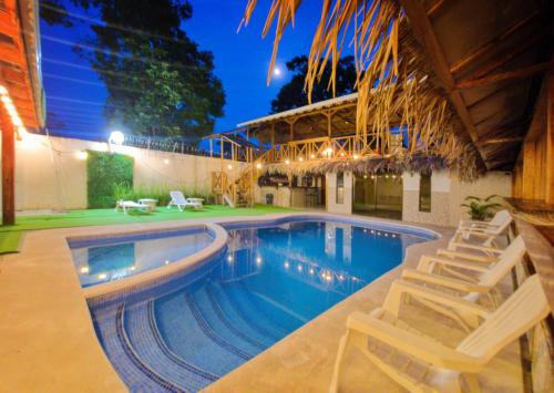 una piscina con 2 sillas y un edificio en Hotel Liah's, en Tortuguero