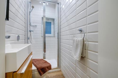 uma casa de banho branca com um chuveiro e um lavatório. em Tranquil Studio in the Heart of Valletta em Valletta