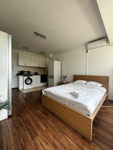 a bedroom with a large bed and a kitchen at Cozy Apartment with Self Check-in near Promenada Mall and Verdi Park in Bucharest