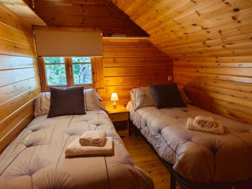 a room with two beds in a log cabin at El Pi Solitari in Camprodon