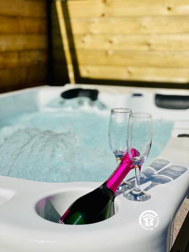 - une bouteille de vin et deux verres dans la baignoire dans l'établissement Gîte & Spa Le Villemachois - 4 étoiles - Jacuzzi couvert - Calme et Indépendant - Clim - Parking - 5 min Carcassonne, à Villemoustaussou