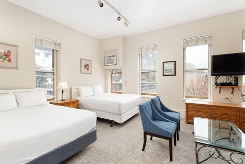a bedroom with two beds and a chair and a tv at Independence Square 213, Spacious Hotel Room with 2 Queen Beds, Wet Bar, and Sitting Area in Aspen