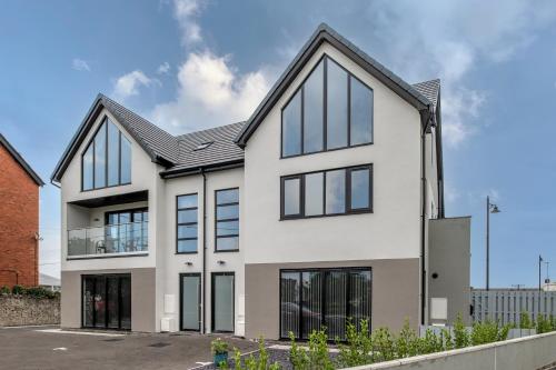 an exterior view of a white house with black windows at Spacious and modern family apartment, central and within walking distance to local amenities in Abergele