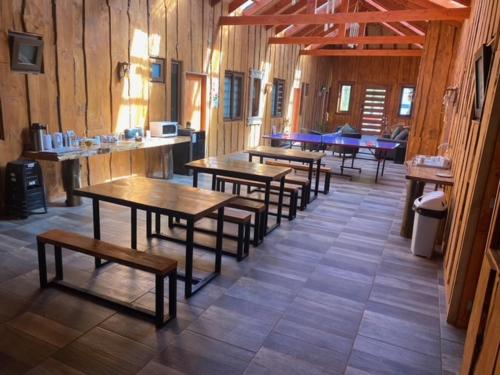 uma fila de mesas e bancos num restaurante em Hostal Entre Los Lagos em Villarrica